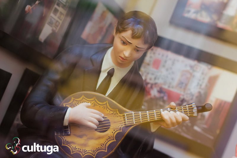 estátua de um homem tocando uma guitarra portuguesa